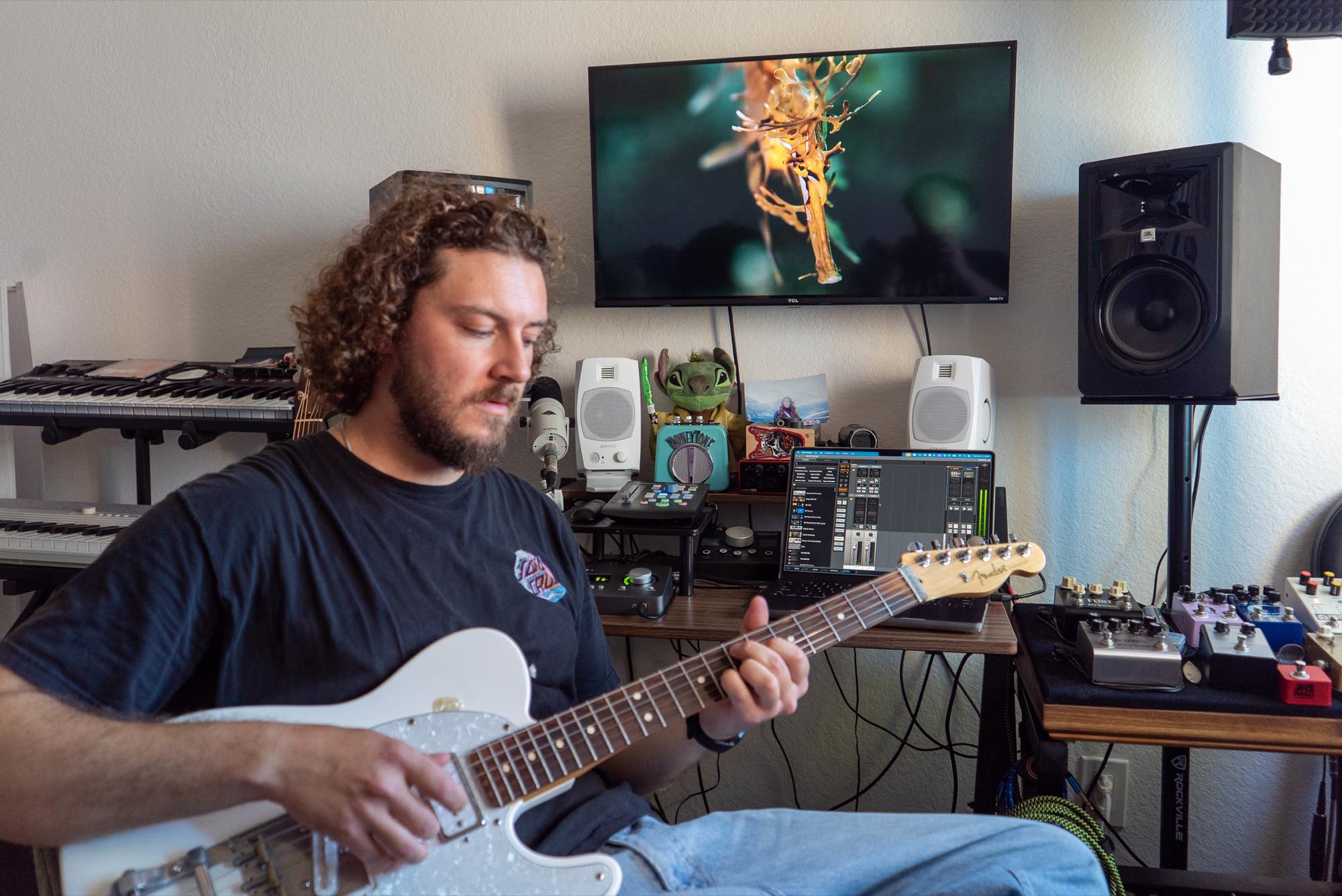 Jordan playing a white electric guitar at the studio desk